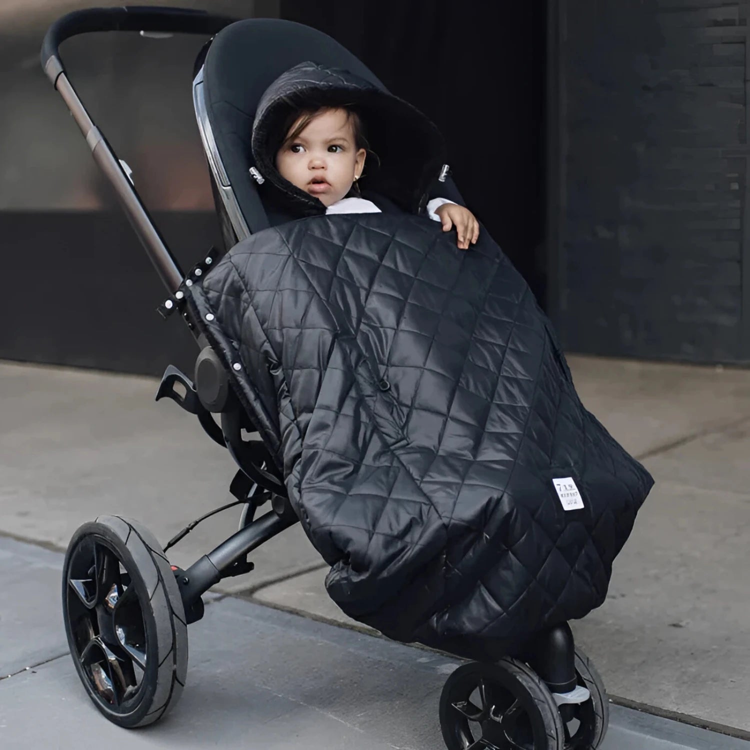 7AM Enfant Baby K-Poncho in black plush, on stroller view
