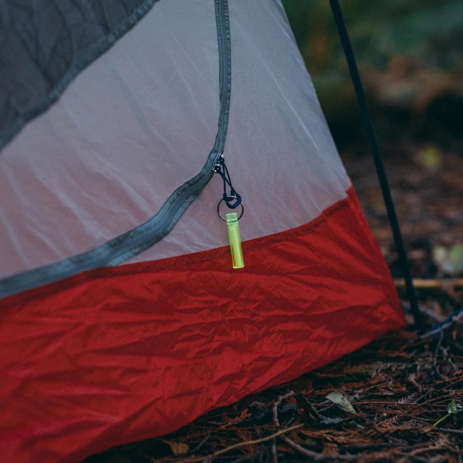 Gear Aid Ni Glo Gear Marker Keychain in green, attached to tent zipper