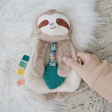 Itzy Ritzy's sloth teether with small ribbon tabs, silicone leaf-shaped teether and sherpa body. Lifestyle view.