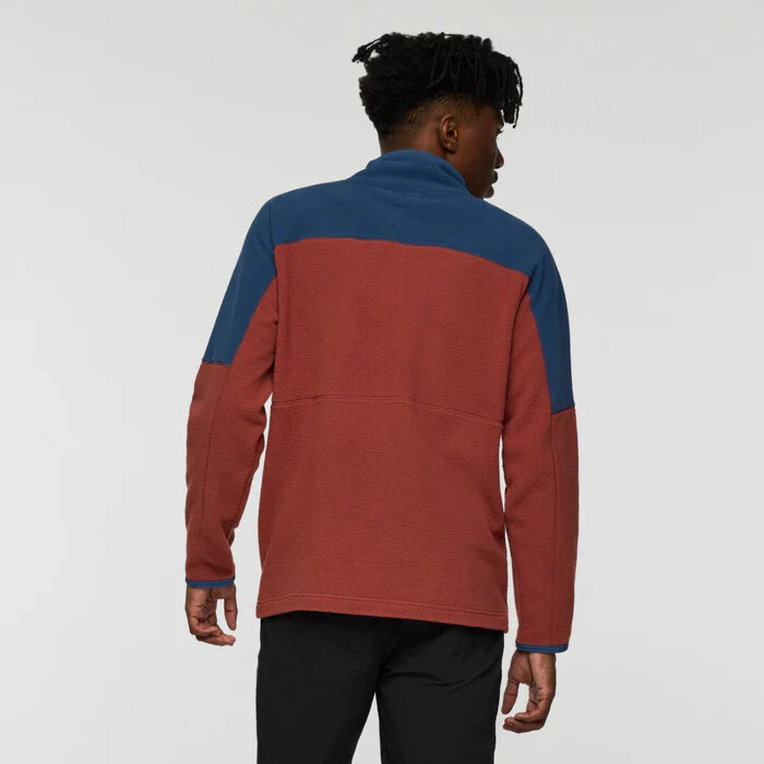 Person wearing a red and blue pullover against a white background