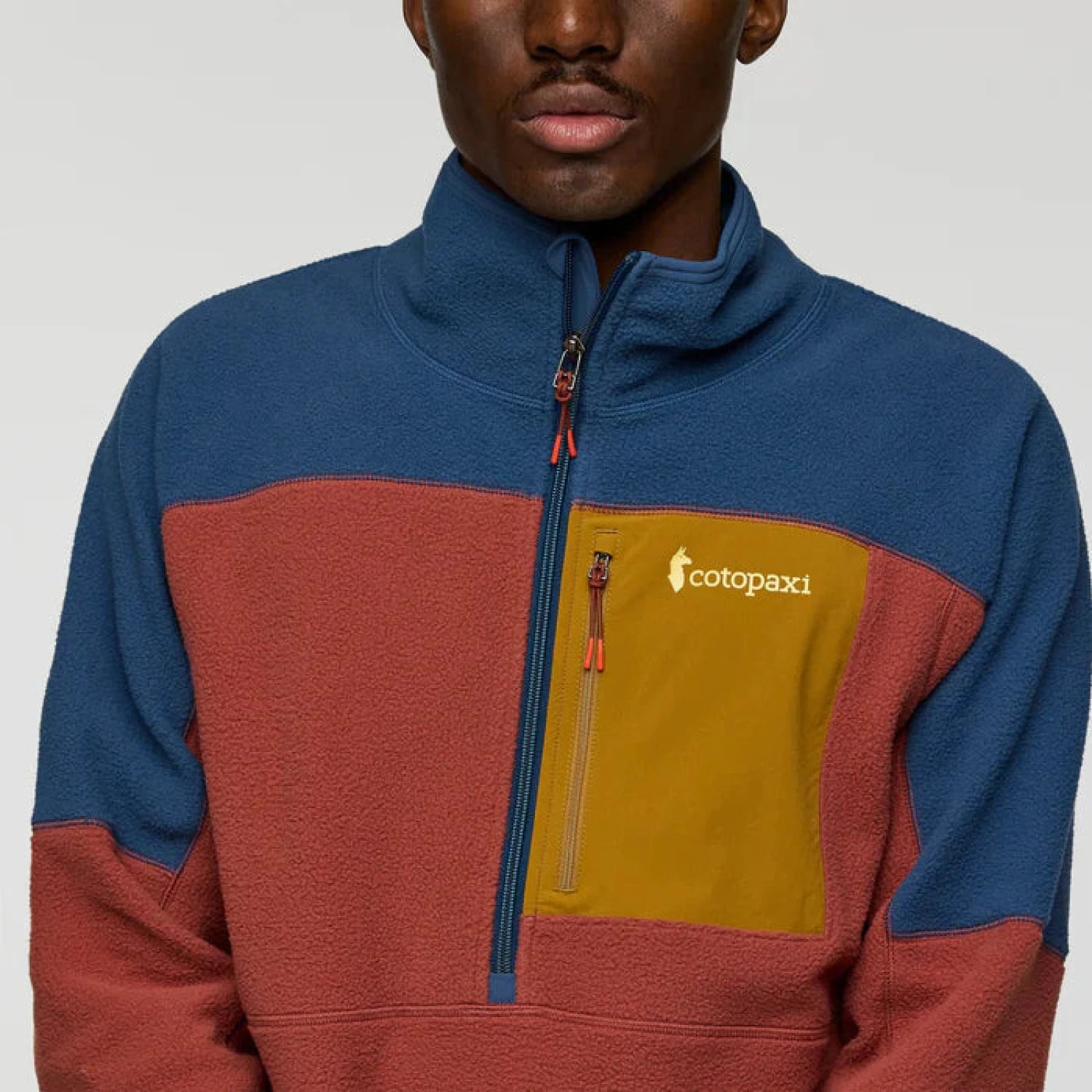 Person wearing a multicolored fleece jacket with a visible brand logo on a plain background