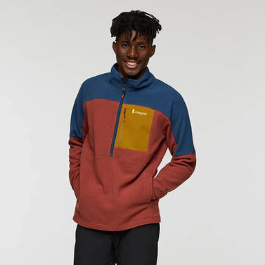 Person wearing a colorful pullover with a visible brand logo on a plain background