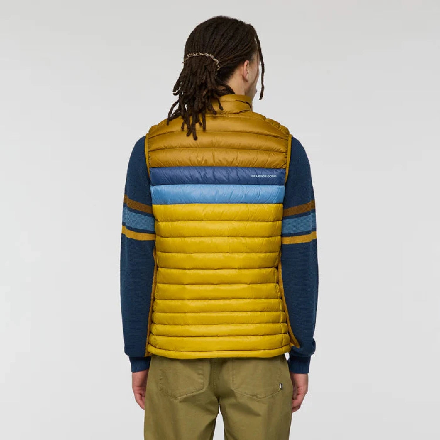 Person wearing a yellow and blue striped puffer vest on a plain background