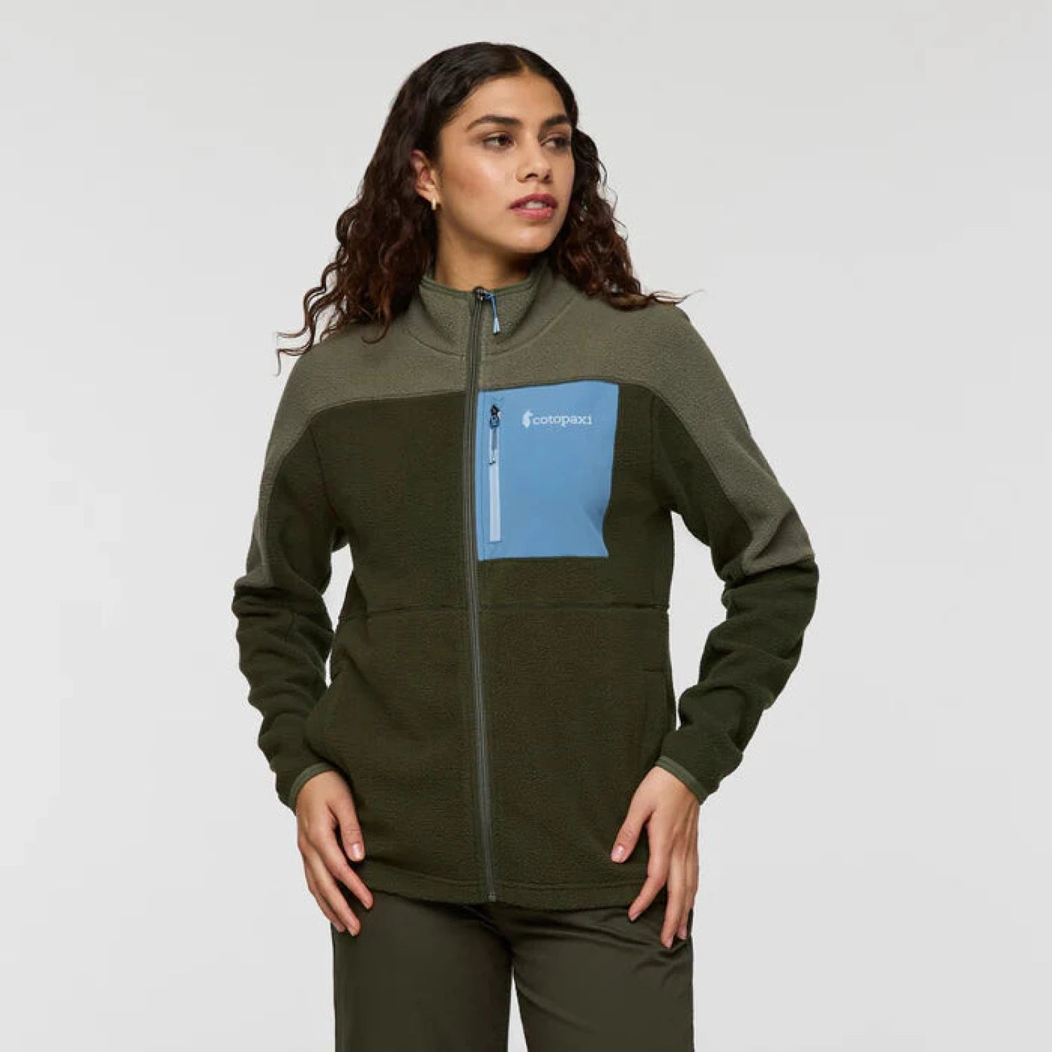 Woman wearing a green fleece jacket with a blue pocket on a white background