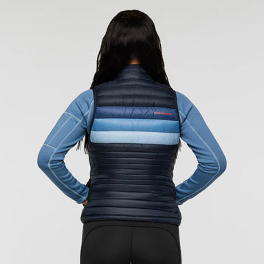 Person wearing a blue and black puffer vest on a gray background