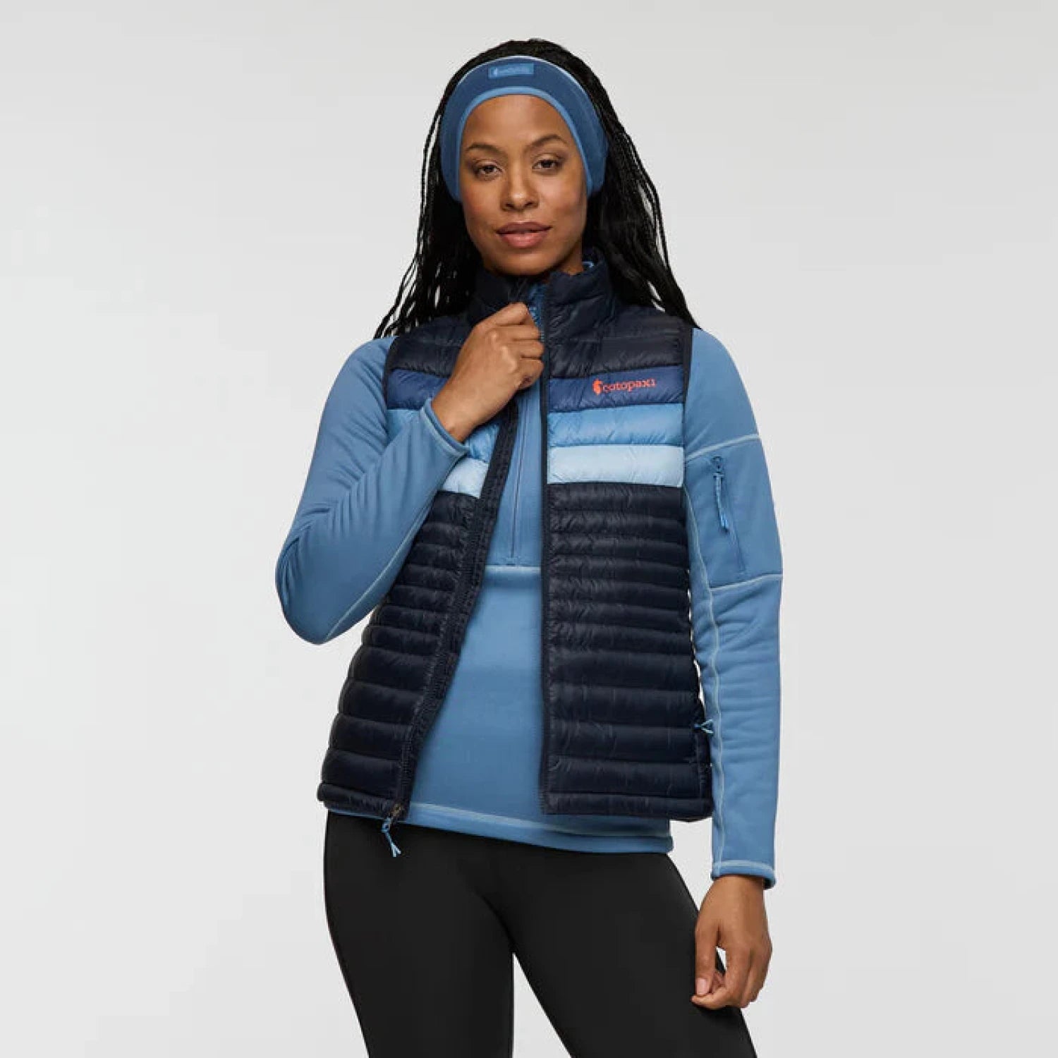 Woman wearing a blue jacket with a navy puffer vest on a white background