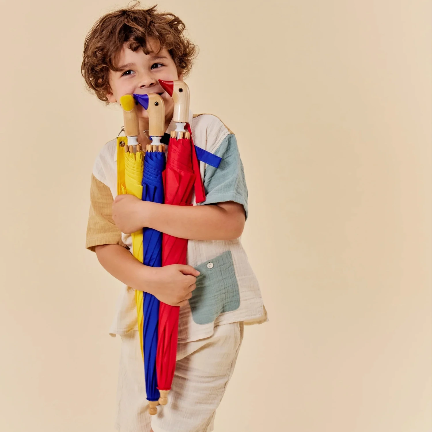 Original Duckhead Duckling Kids Umbrella, kid holding red, blue and yellow packed umbrellas