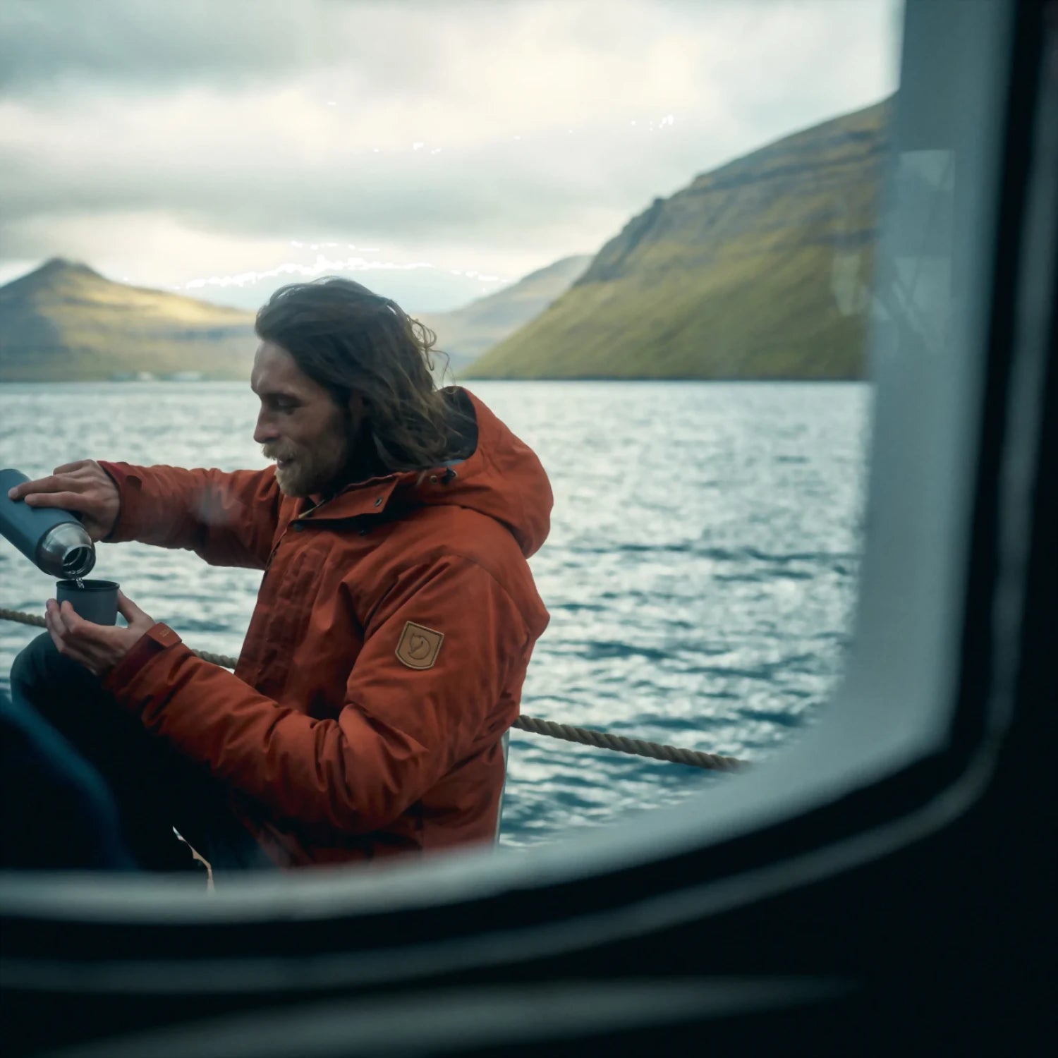 Fjällräven Men's Skogsö Padded Jacket in autumn leaf model on a boat view