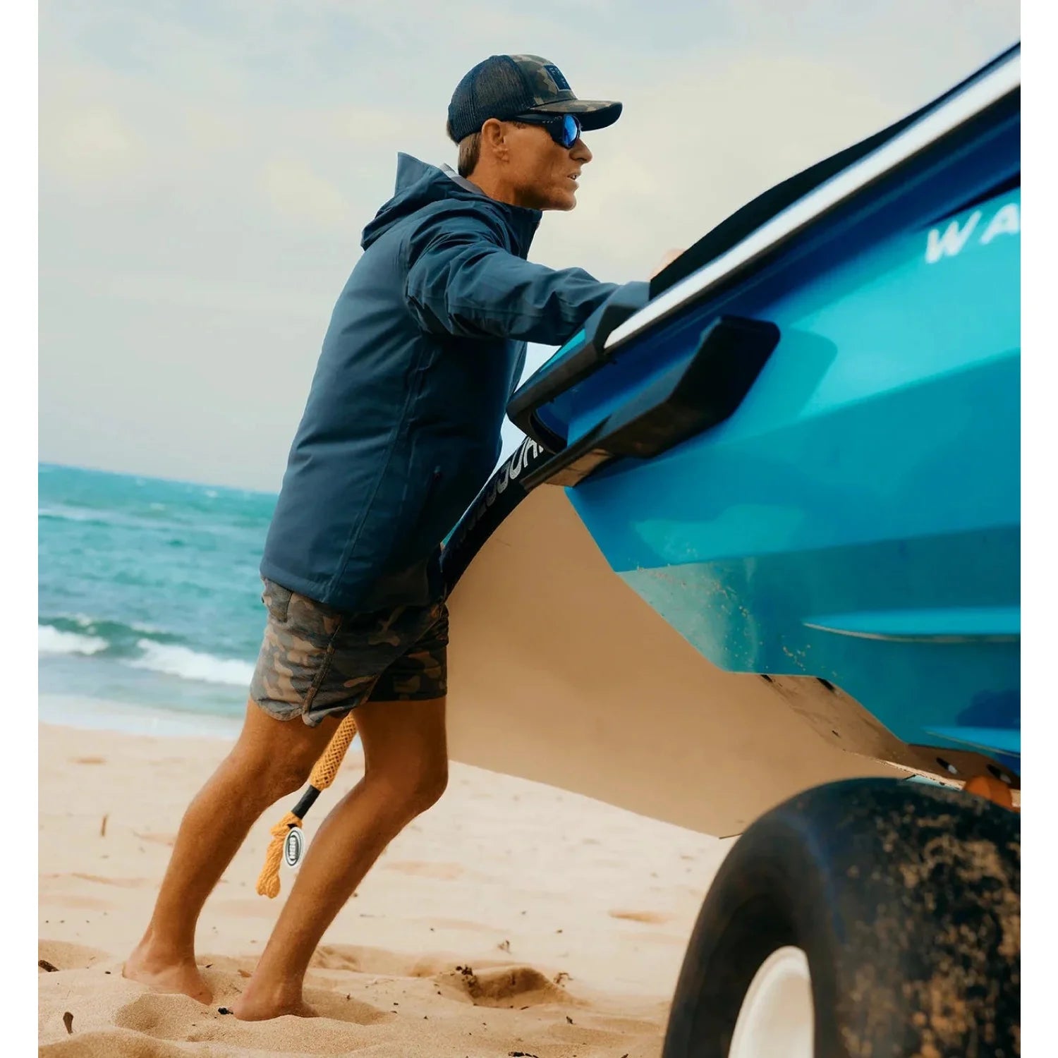 free fly mens cloudshield rain jacket in storm cloud model on beach near boat 