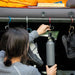 the gear aid heroclip small carabiner is being used by a woman in a grey shirt to hang a waterbottle and shoes 