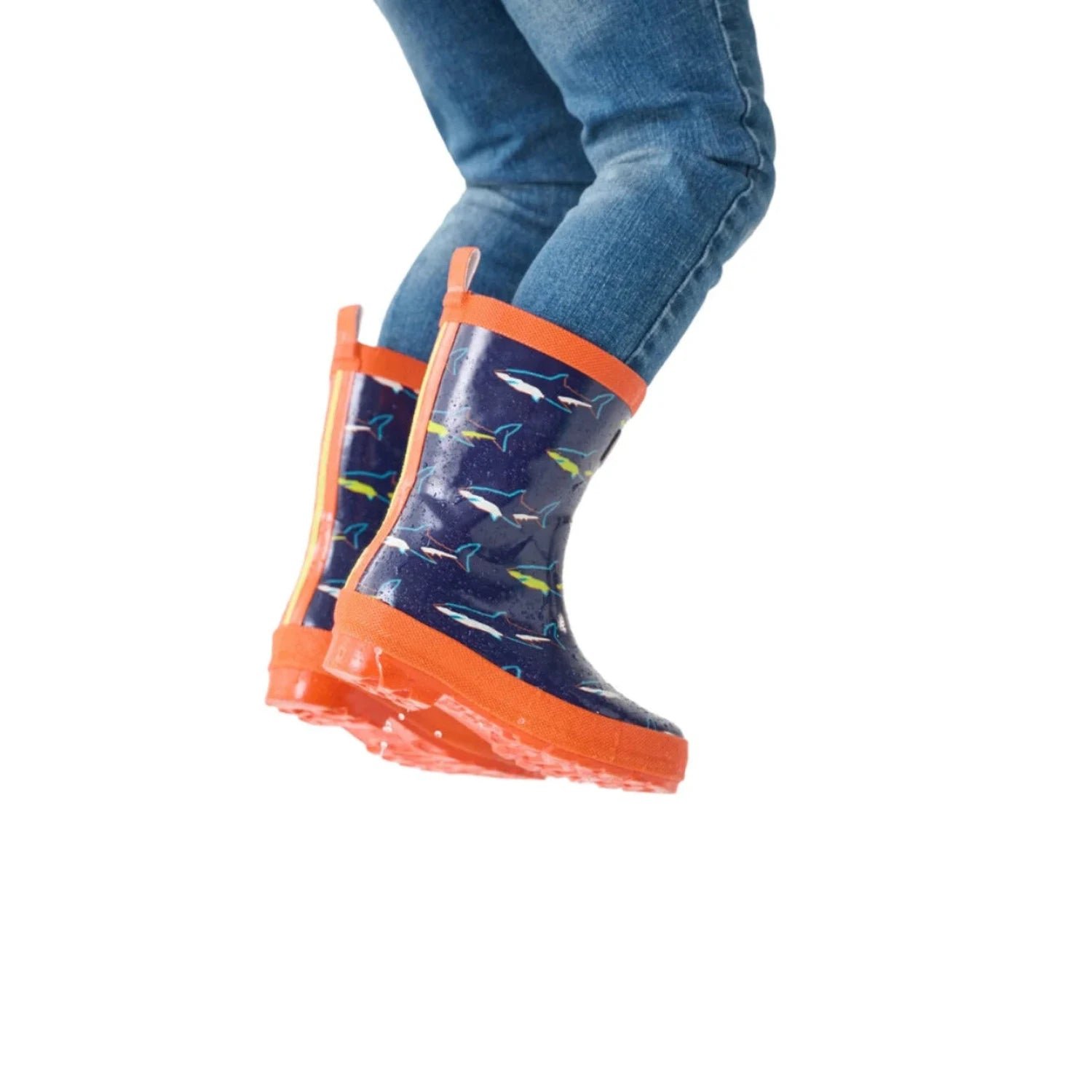 Hatley Kid's Rain Boots shown in the Shiny Sharks color option. Shown on model jumping.