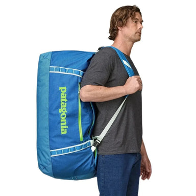 Patagonia Black Hole® Duffel Bag 100L shown in the Matte Vessel Blue color option on model's back, side view.