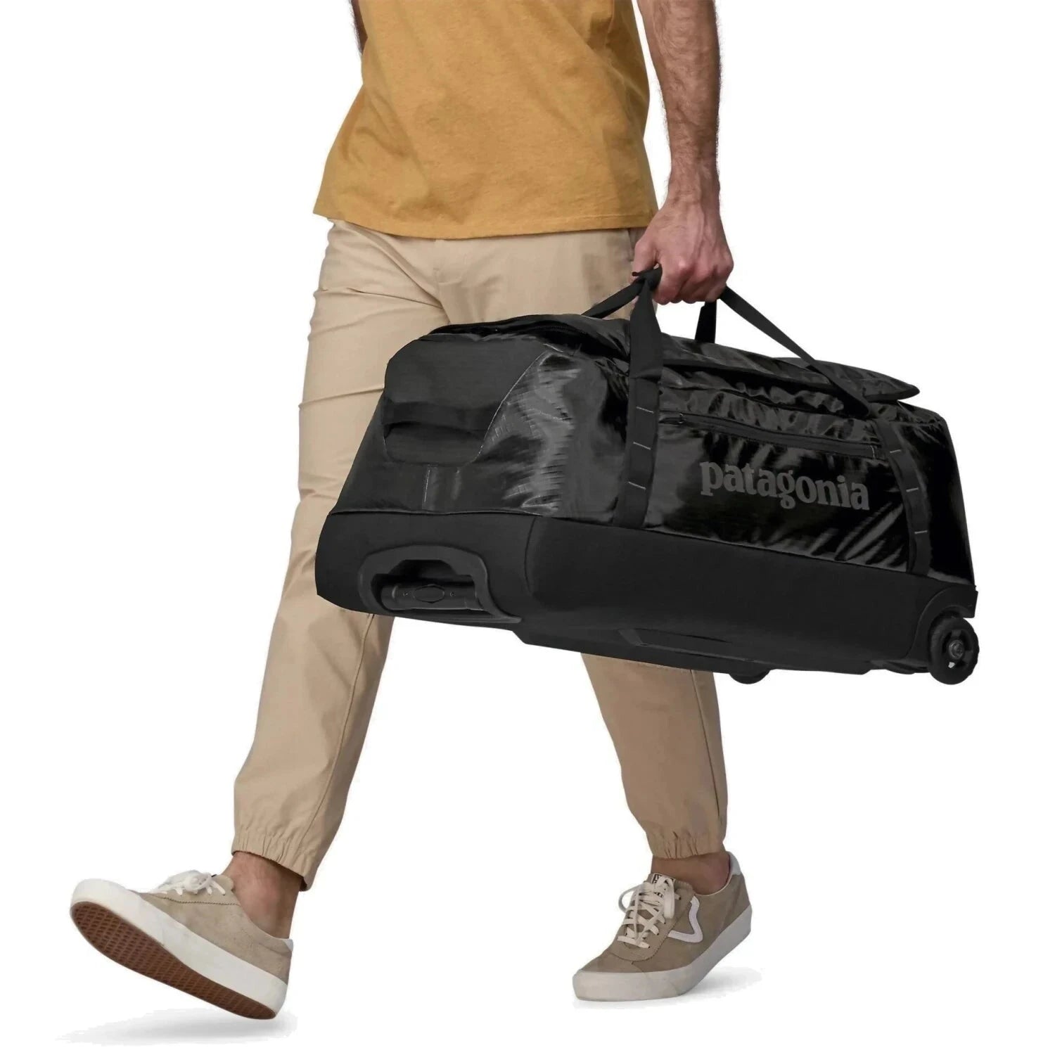 Patagonia Black Hole® Wheeled Duffel Bag 70L, Black, front and side view of model holding bag 