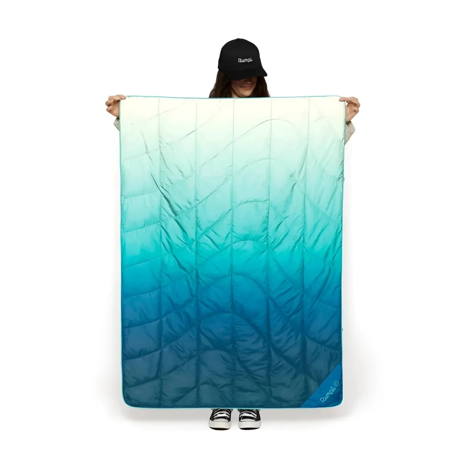 Rumpl Travel Puffy Blanket in deepfoam fade, held up in front of model