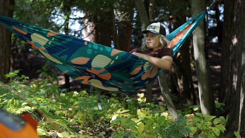 Image of model in hammock in the woods