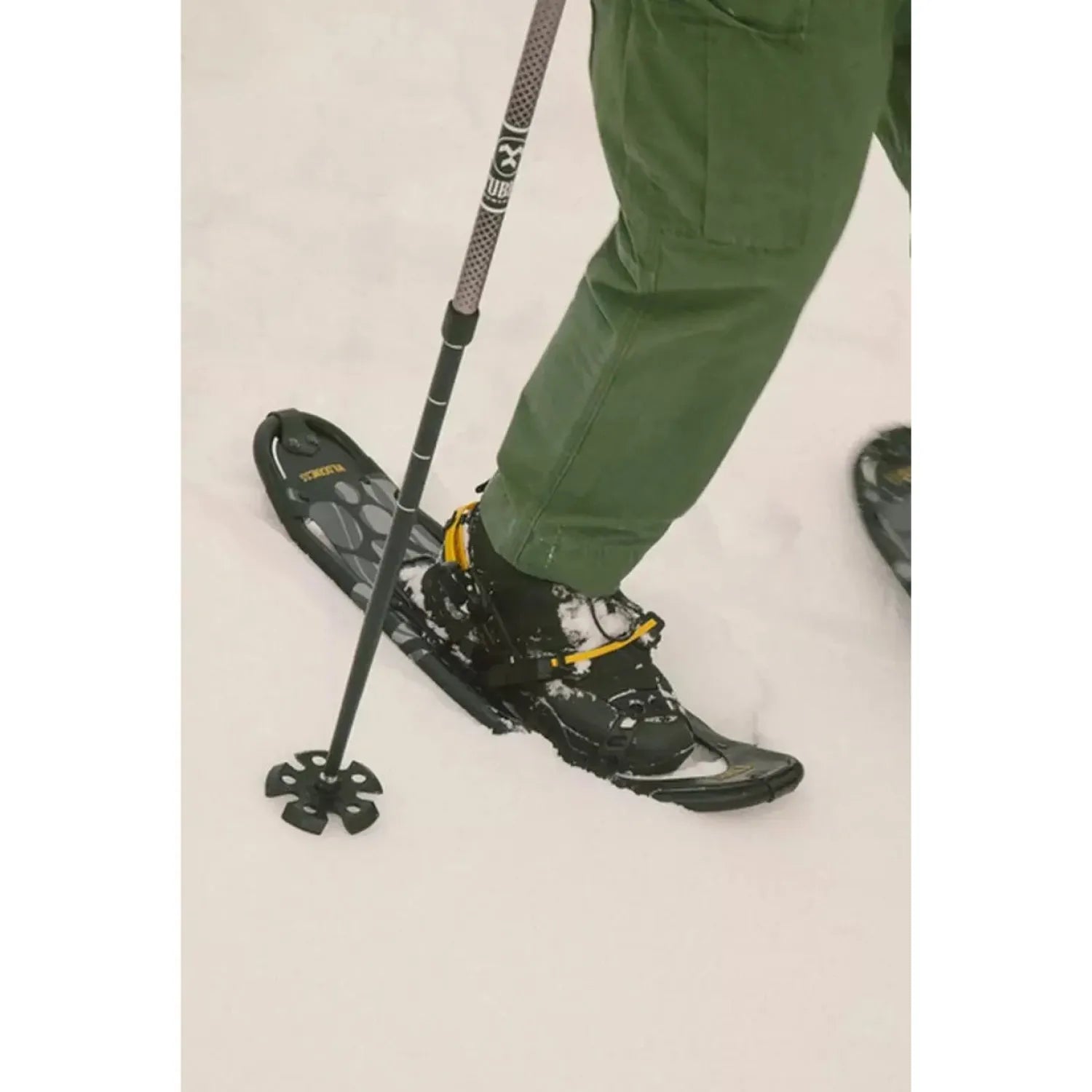 Tubbs Men's Wilderness Snowshoe in Black, lifestyle view on man trekking through deep snow with snowshoes on..